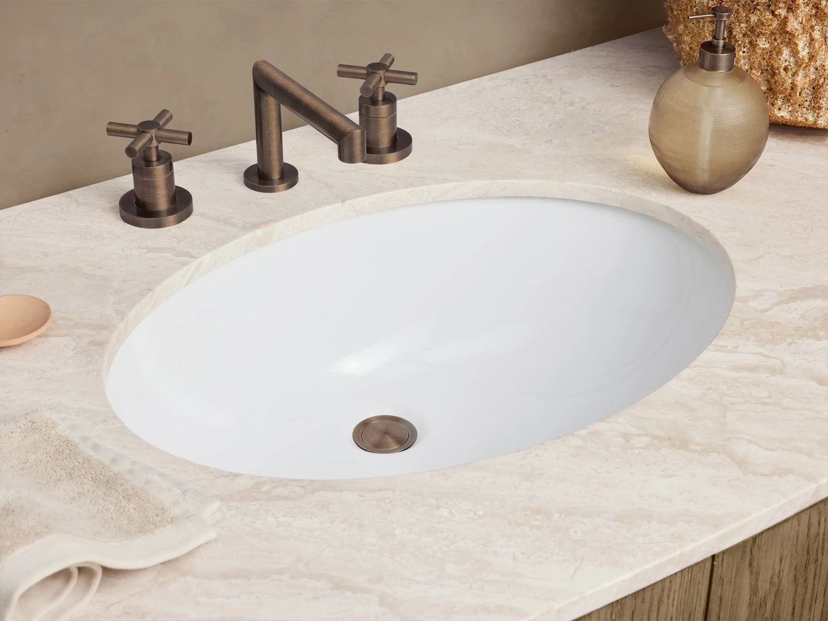 Danny Wide Single Vanity: light oak cabinet with rounded ends, white marble top, oval sink, central double doors, six curved drawers, dark bronze hardware.