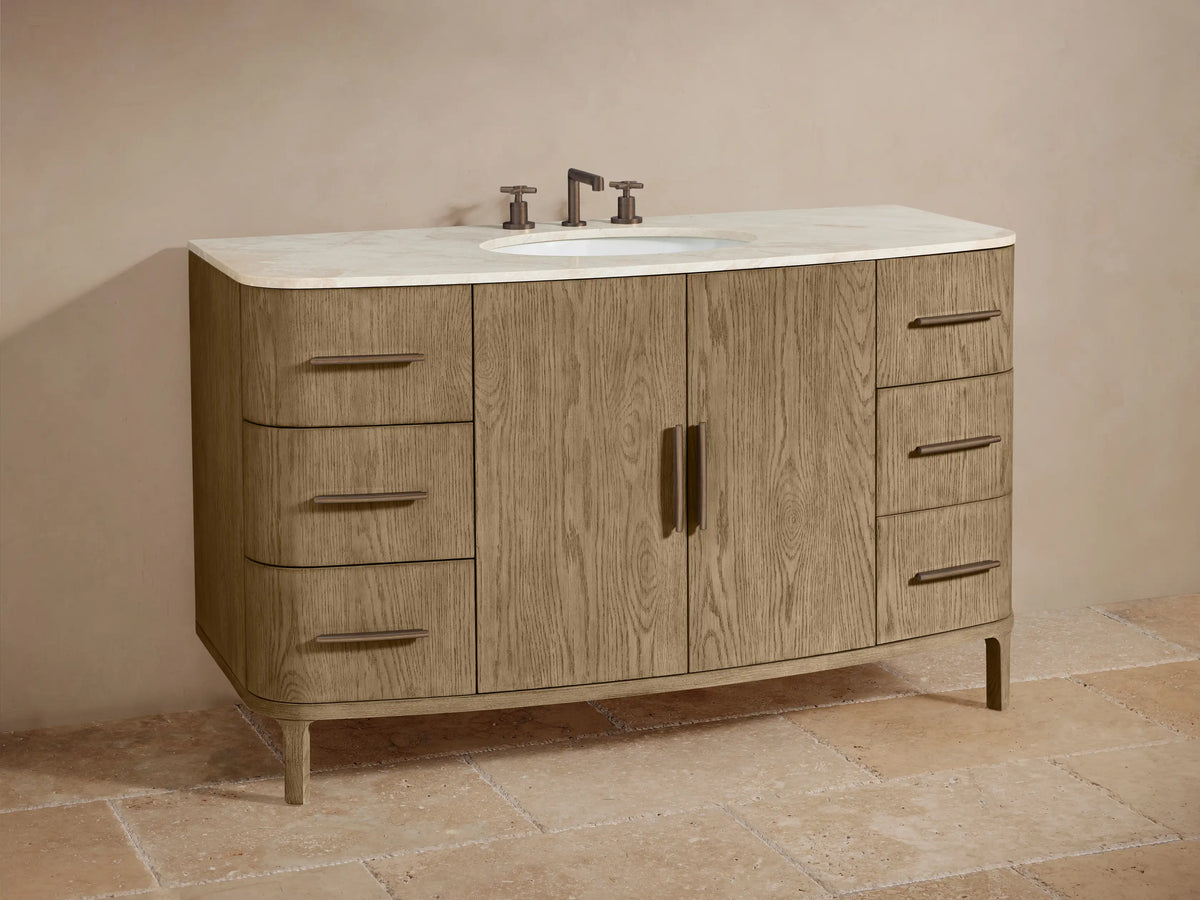 Danny Wide Single Vanity close-up. Light oak wood with curved front, light marble top. Open drawer reveals a white towel.