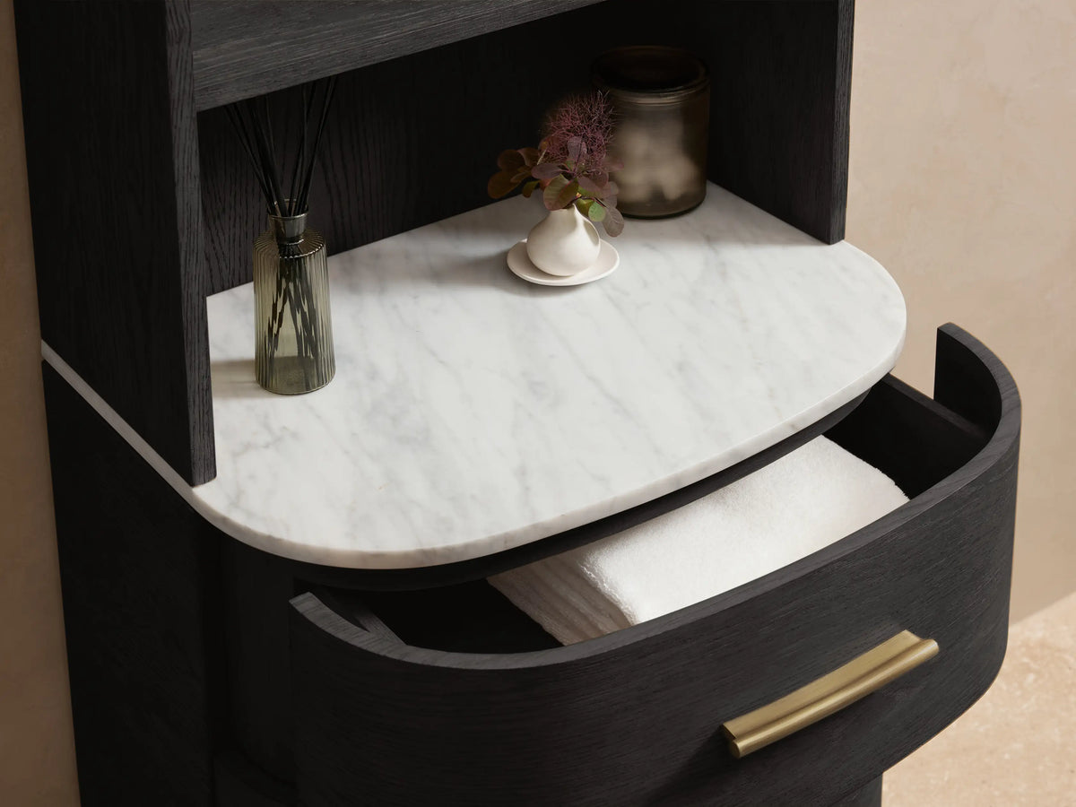 Danny Bath Cabinet, dark wood, arched top. Upper shelves, white stone top, 3 curved drawers with brass pulls. On stone floor.