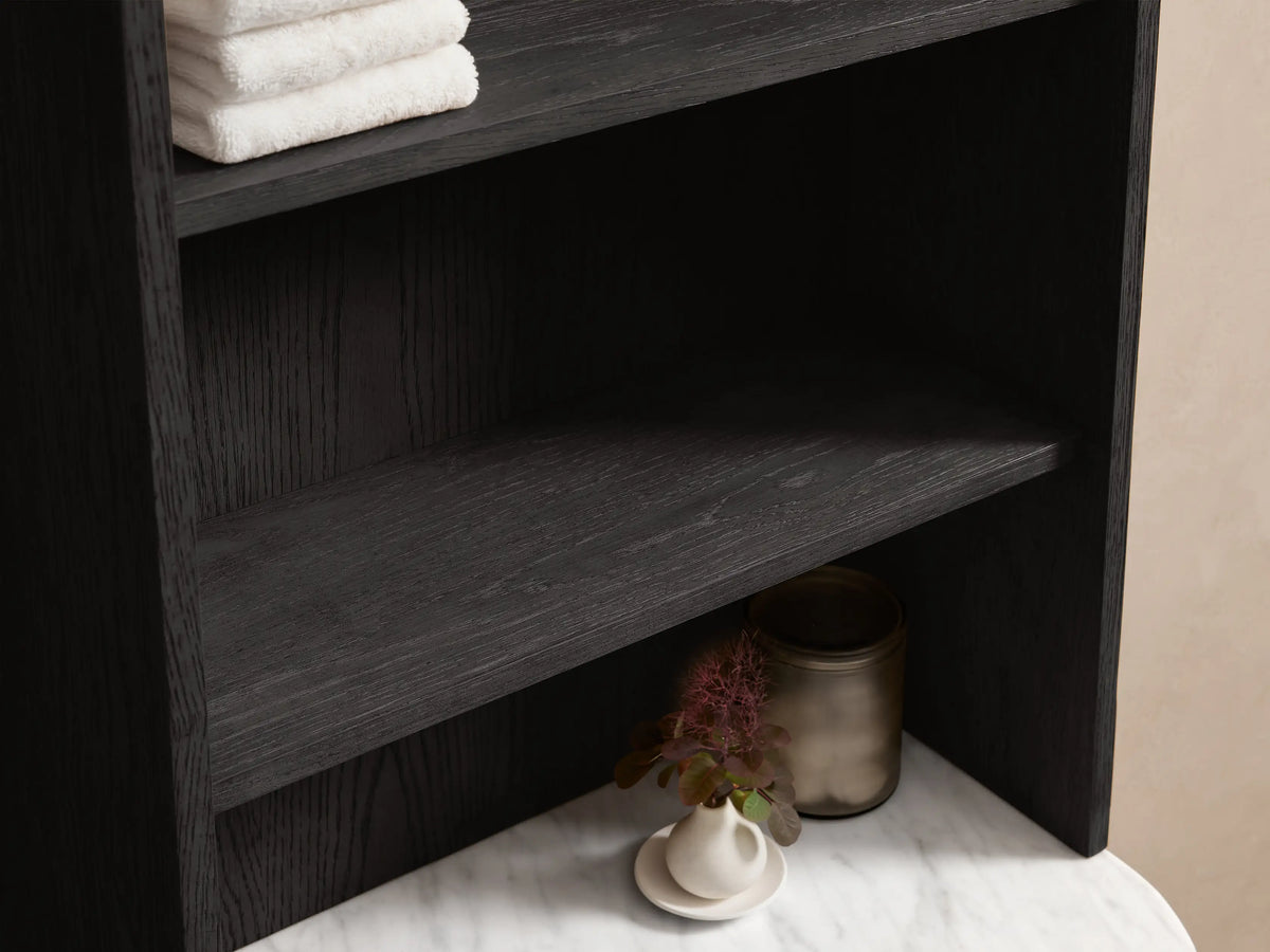 High-angle of dark oak Danny Bath Cabinet with white marble top, diffuser, plant, open drawer with towels & brass pull.