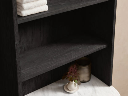 High-angle of dark oak Danny Bath Cabinet with white marble top, diffuser, plant, open drawer with towels & brass pull.