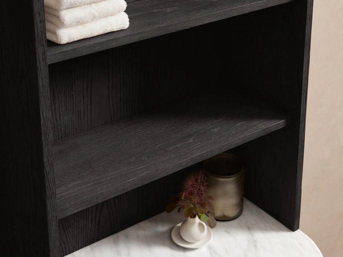 Angled view of a dark gray Danny Bath Cabinet, white marble top, and open drawer with a white towel. Silver handle, diffuser and vase.