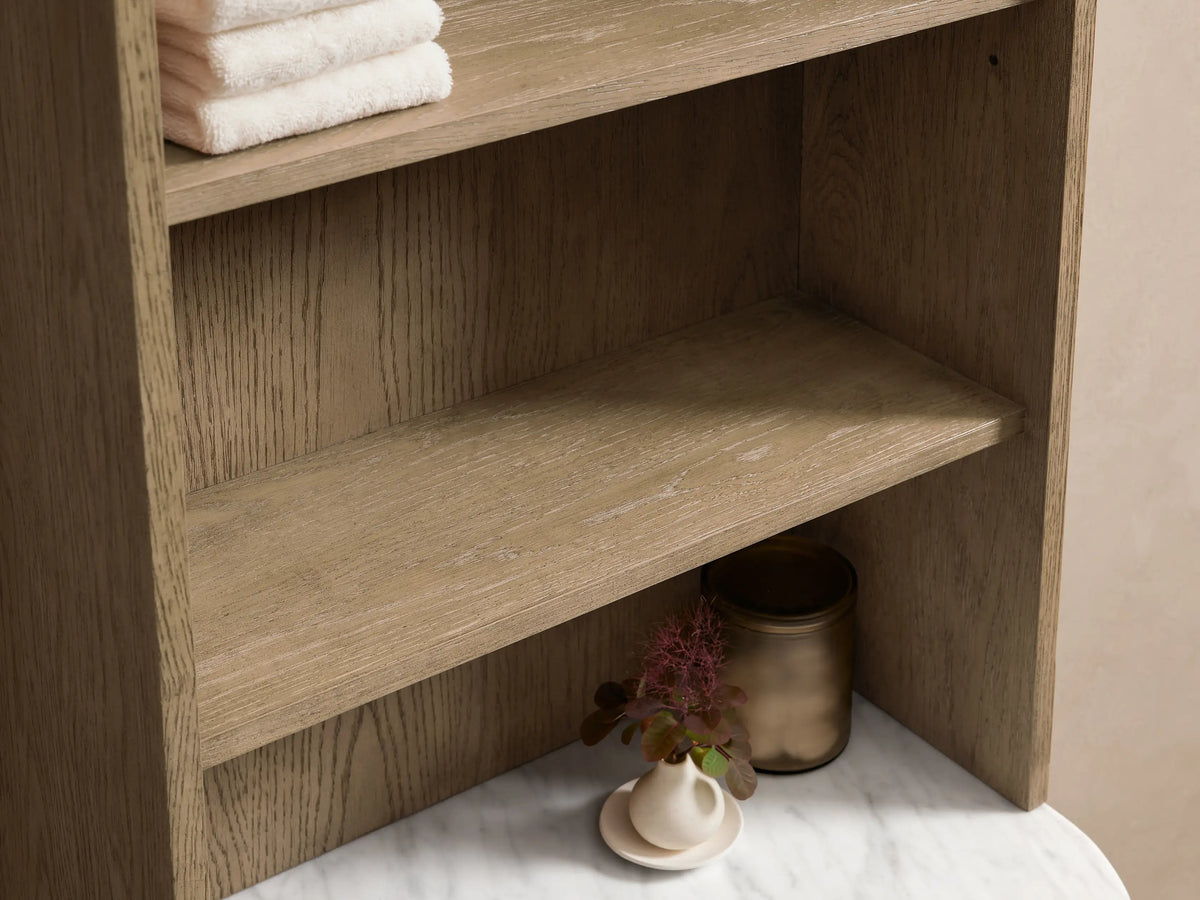 Danny Bath Cabinet: light oak wood, curved white marble top. Open drawer with white towel, bronze handle, decor on top.