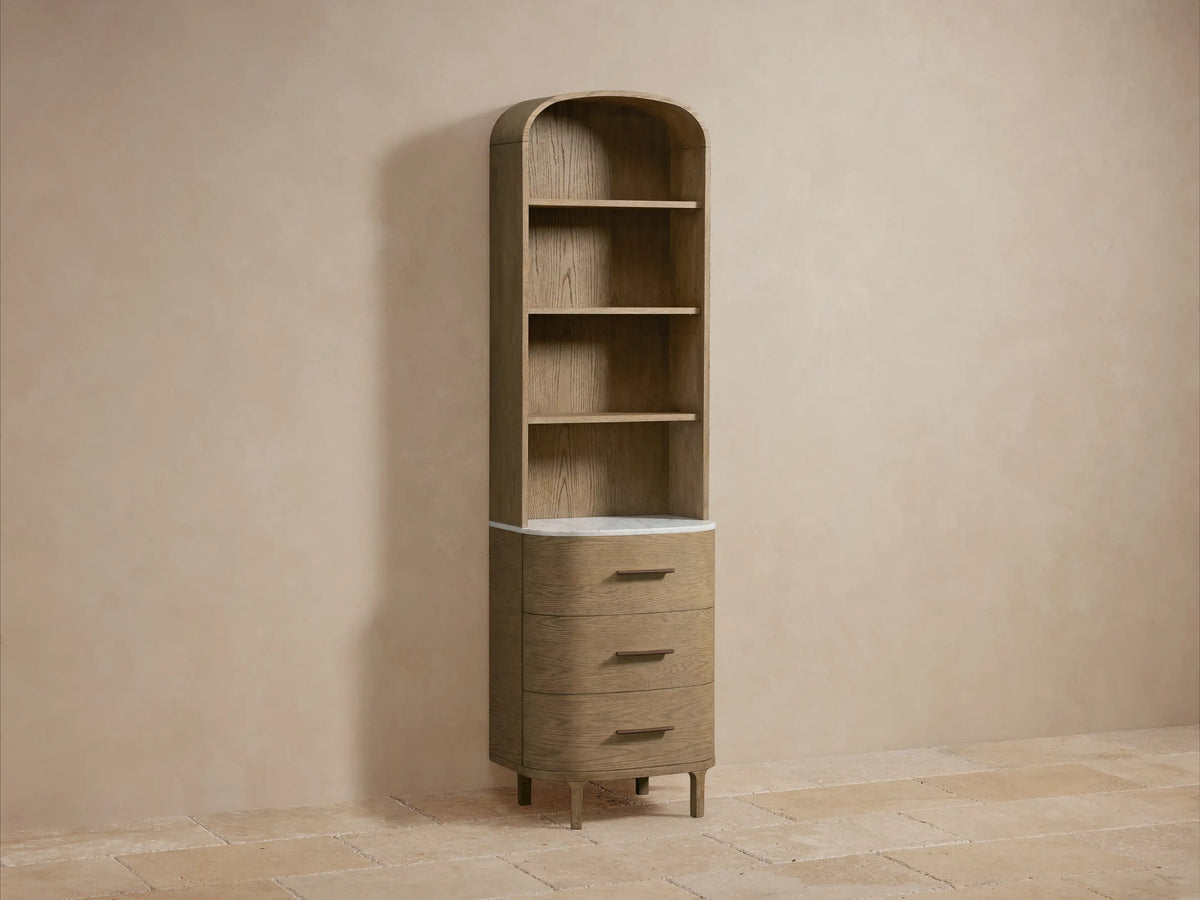 Close-up of Danny Bath Cabinet detail showing light oak shelves. White towels on upper shelf, white marble, vase with plant, bronze jar on lower.