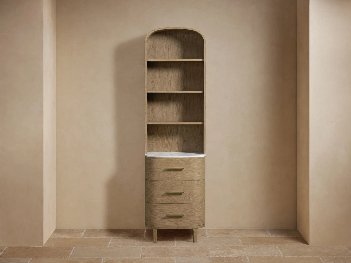 Alt text: Close-up of Danny Etagere, featuring oak wood shelves with a Carrara marble stone top. A small vase and jar sit on the marble.