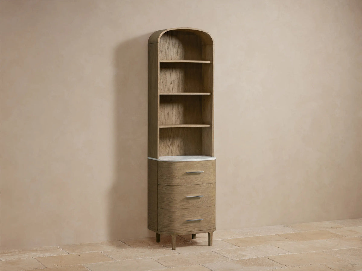 Danny Etagere with oak wood finish, Carrara marble top, three lower drawers, and open shelves displaying decor in a neutral room.