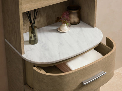 Danny Etagere in light oak with three open shelves, Carrara marble top, and three drawers with brass hardware on light brown flooring.
