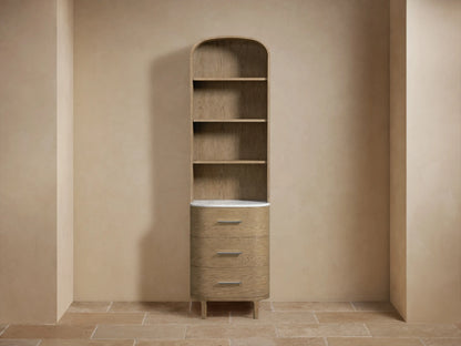 Oak wood Danny Etagere with light brown finish, stone top, two shelves, towels on top, and a decorative item on the bottom shelf.