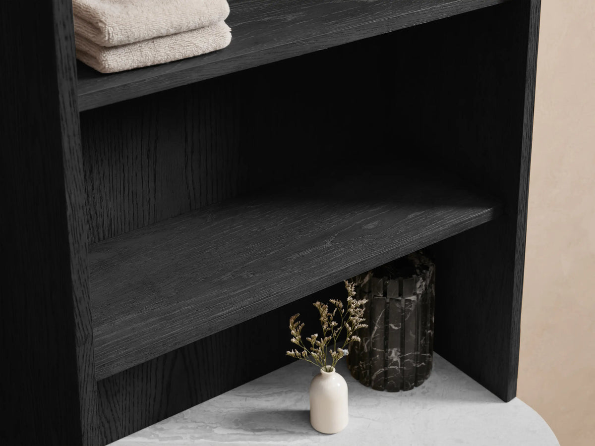 Top section of black oak Danny Bath Cabinet with rounded creamy marble surface. Partially open drawer reveals towels. Polished nickel handle.