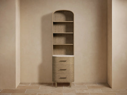 Arched, tall Danny Bath Cabinet in light oak wood, featuring 4 open shelves, white marble top, & 3 rounded drawers with brass pulls.