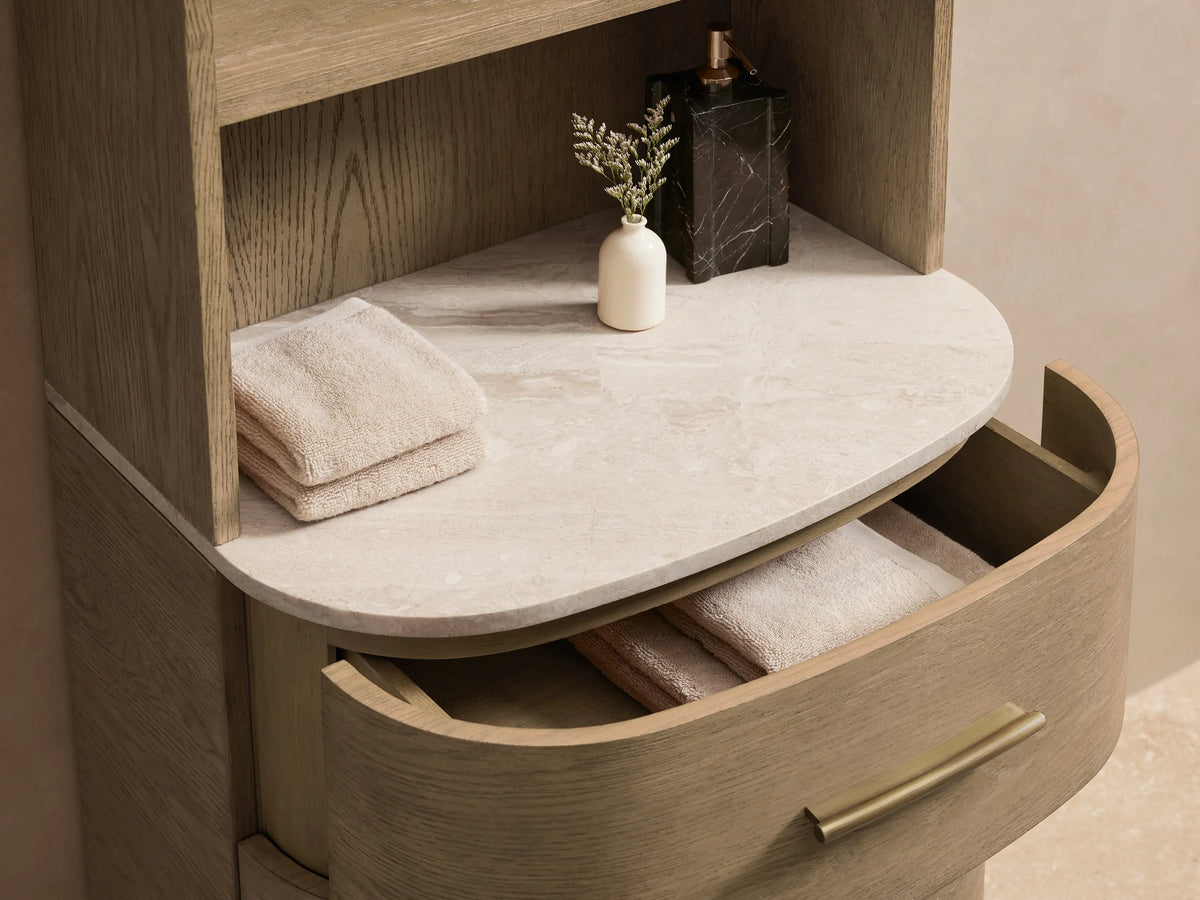 Danny Etagere with oak wood and plywood frame, four open shelves, three drawers with brass hardware, and stone top against a beige wall.