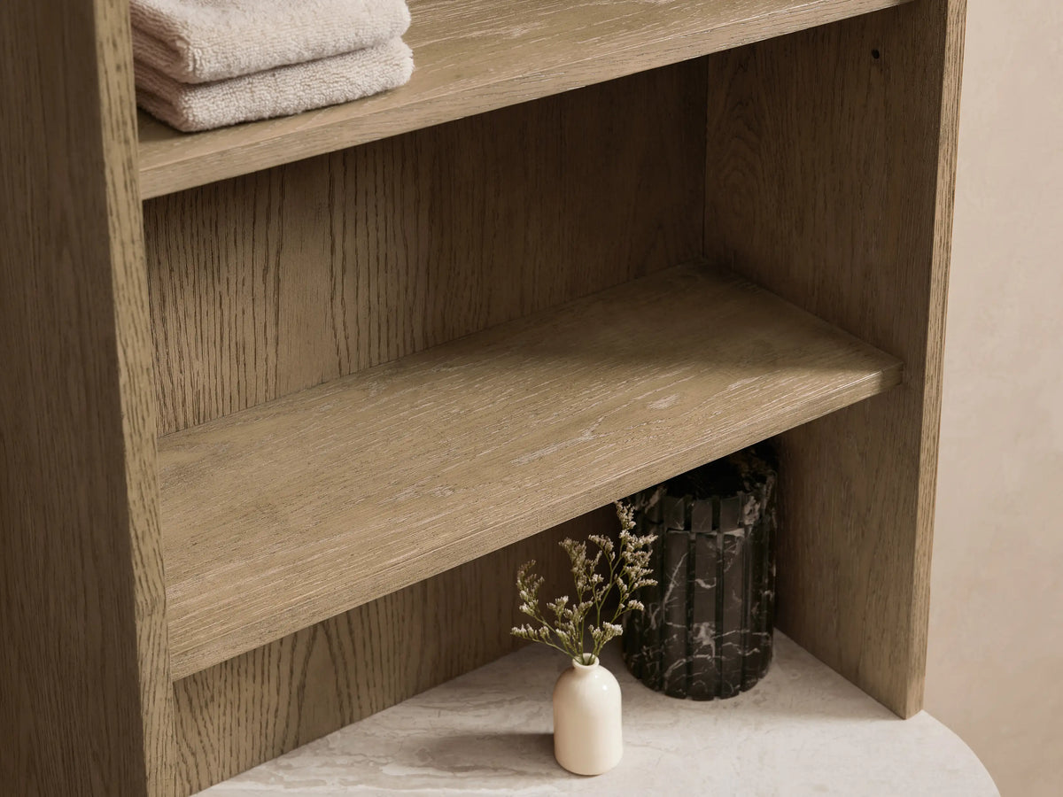 Danny Etagere with cream marble stone top, displaying folded towels, a small vase with greenery, and a black bottle, open drawer with brass handle.