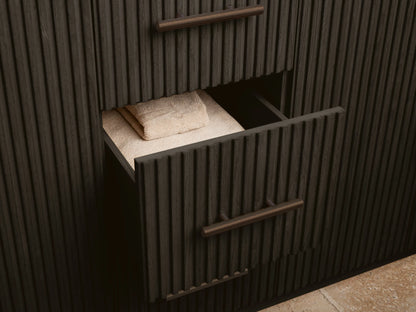 Close-up of open dark oak Finnley Double Vanity cabinet door with fluted texture, bronze handle. Inside: sponge in bowl, white towels.