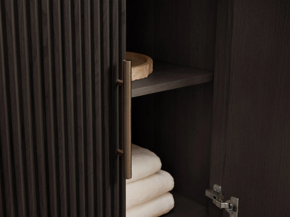 Finnley Double Vanity, front view. Dark ribbed wood cabinet with light veined marble top, two bronze faucets, drawers, and doors.