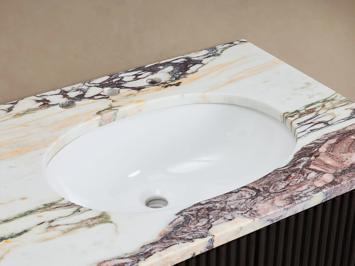 Finnley Double Vanity: White oval sink, richly veined white, pink, green, gold marble top, bronze faucet, stone soap, towel.