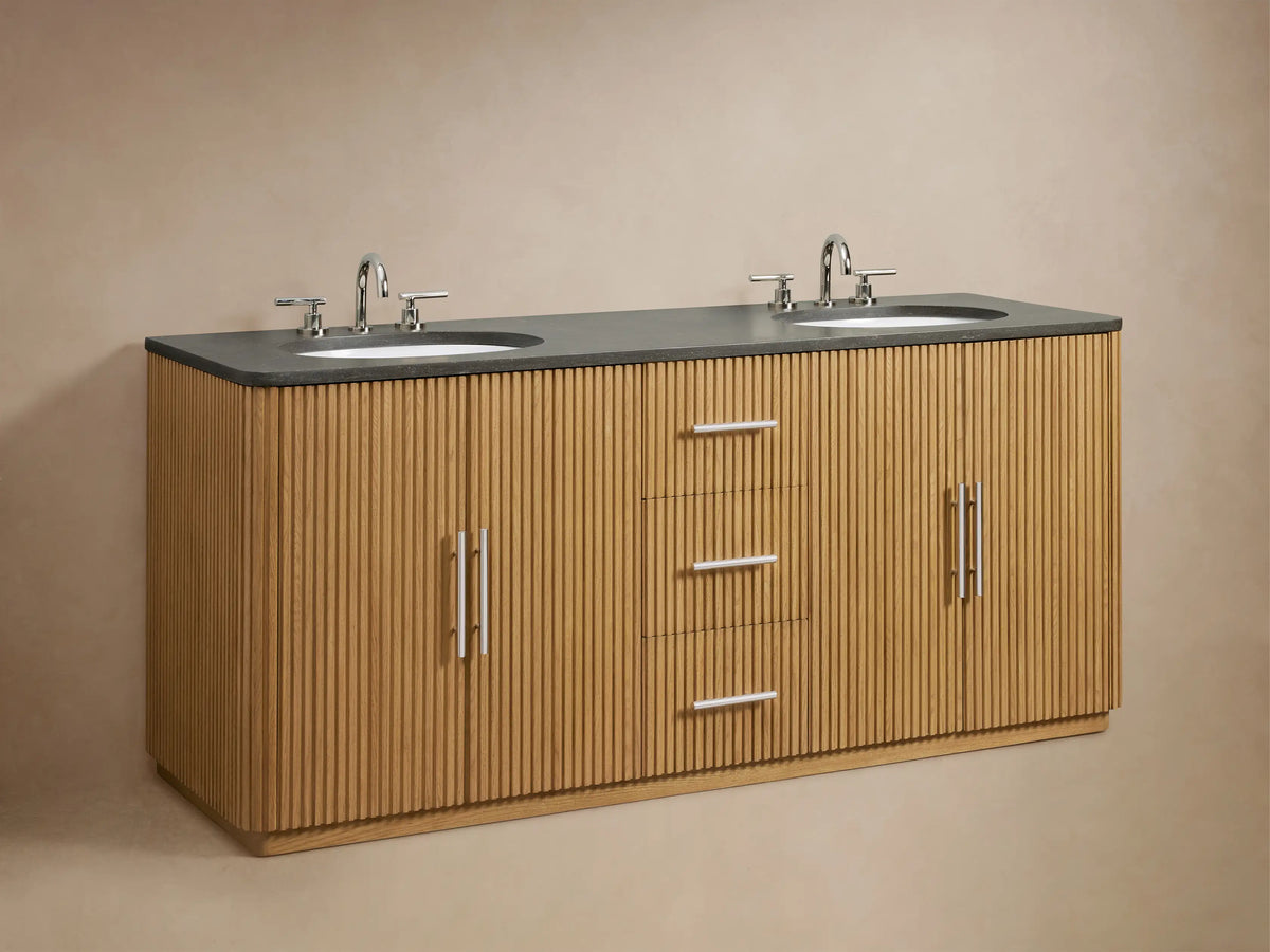 Finnley Double Vanity in oak wood with fluted drawer fronts, soft-close drawers open, revealing a towel and bottle inside. Dark stone top visible.