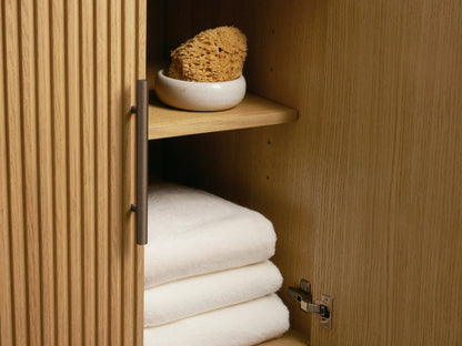 Finnley Double Vanity: Close-up of white oval sink, white marble countertop, bronze faucet, fluted wood base. Towels & soap.