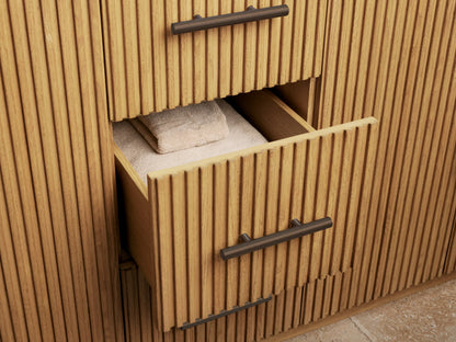 Close-up of Finnley Double Vanity's open light oak cabinet, showing fluted door, dark pull, natural sponge in bowl, and white towels.
