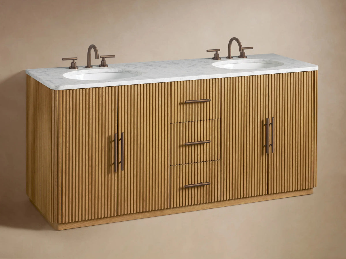 Close-up of Finnley Double Vanity, ribbed oak wood. One drawer open revealing folded beige towels. Dark bronze pulls.