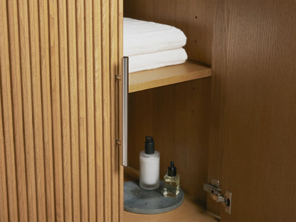 Oval ceramic sink set in Carrara marble countertop with three polished nickel faucets. Soap dispenser and tray on side.