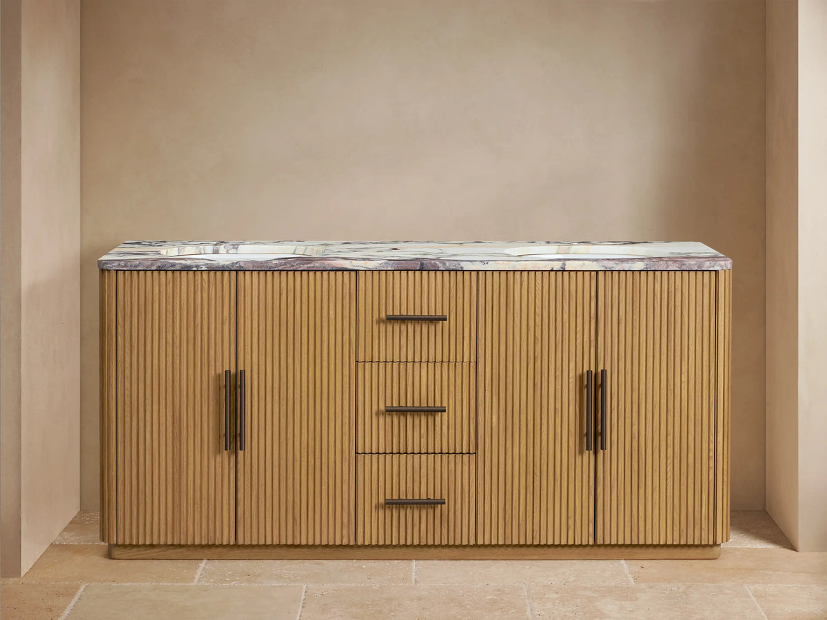 Finnley Double Vanity in light oak with reeded fronts, purple-veined marble top, 2 dark faucets. Left cabinet open with towels.