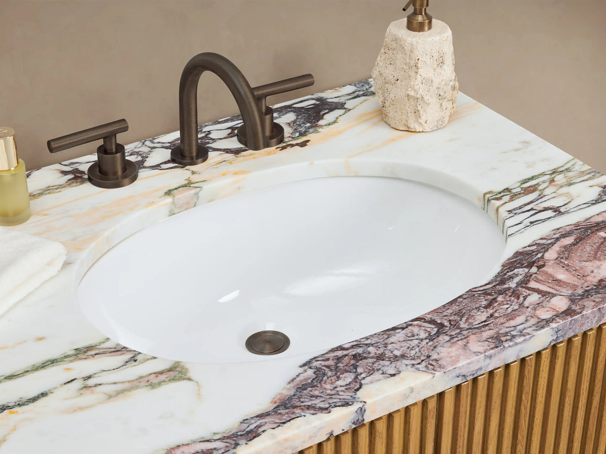 Finnley Double Vanity. Light oak wood with ribbed texture, white/purple veined marble top. Two cabinet doors, three central drawers, bronze hardware.