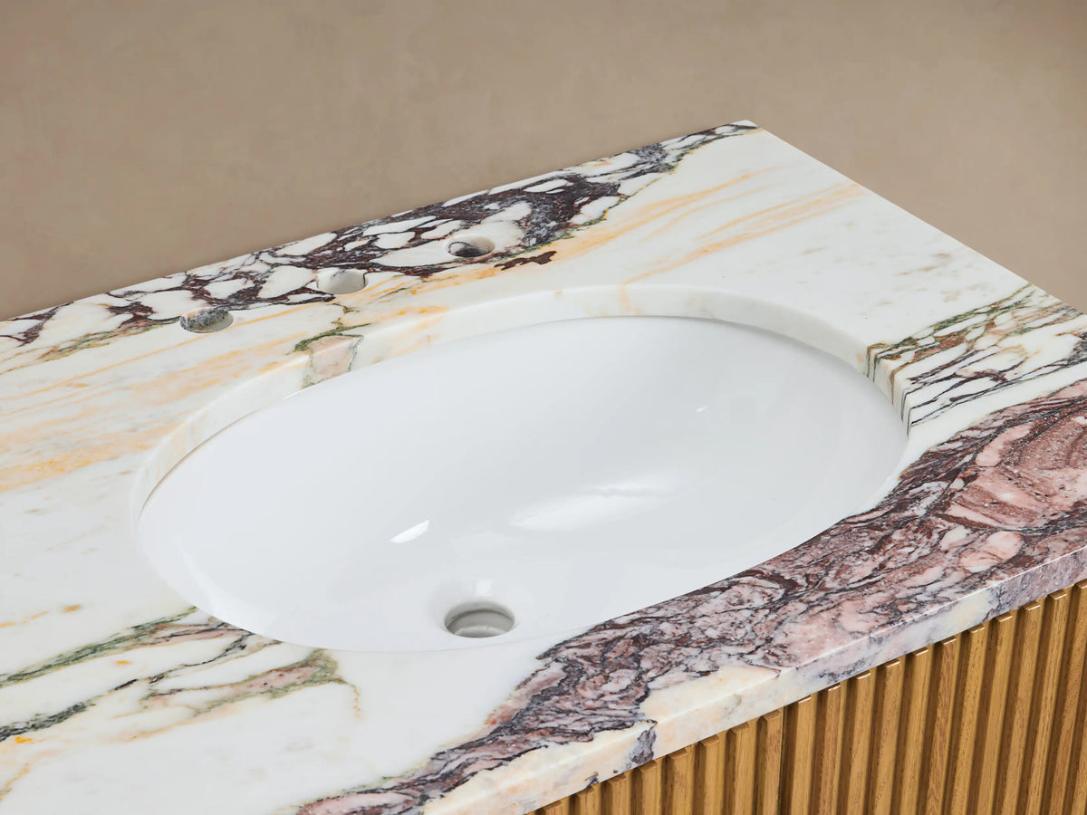Close-up of Finnley Double Vanity's marbled countertop with white oval sink, bronze faucet, stone dispenser, and ribbed wood.