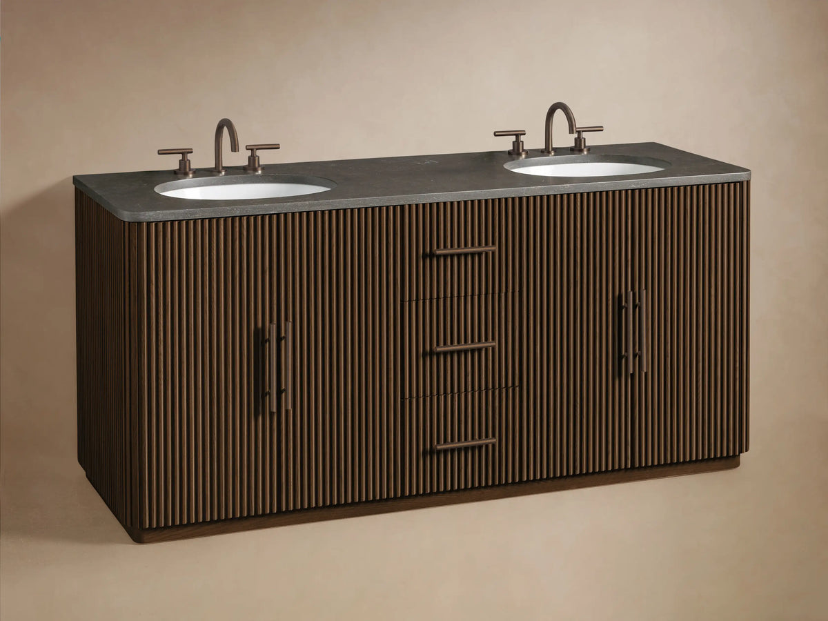 Finnley Double Vanity: dark slatted wood, dark stone top, two white oval sinks, bronze faucets. Left cabinet door open with towels.
