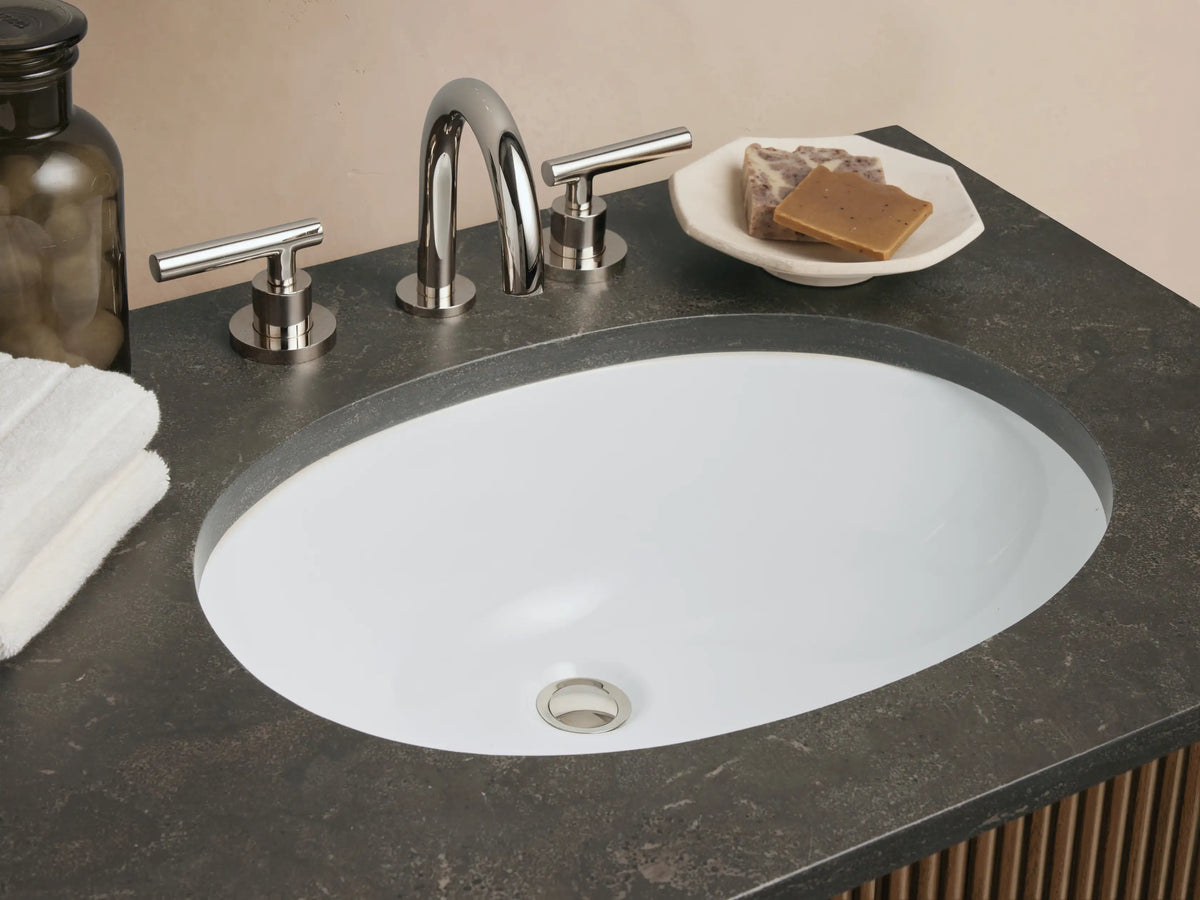 Dark fluted Finnley Double Vanity with dark stone top, two white oval sinks, three central drawers & side cabinets with metallic pulls.