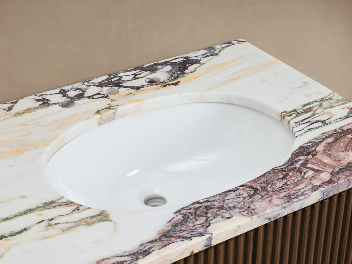 Finnley Double Vanity: White oval sink in Calacatta Viola marble top with rich reddish-brown veining, bronze faucet. Ribbed wood base.