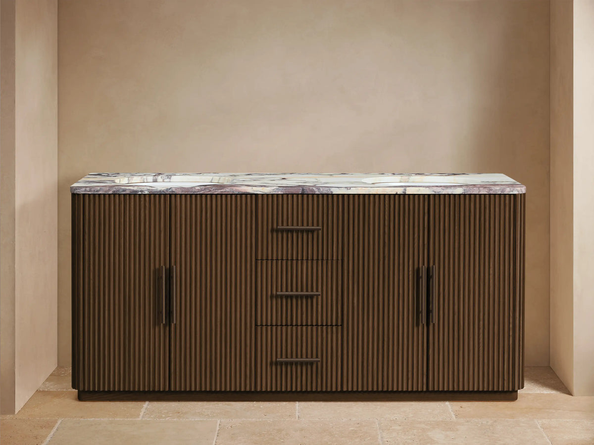 Finnley Double Vanity: dark reeded wood cabinet, reddish-brown marble top. Partially open drawer reveals white towels & bottles.