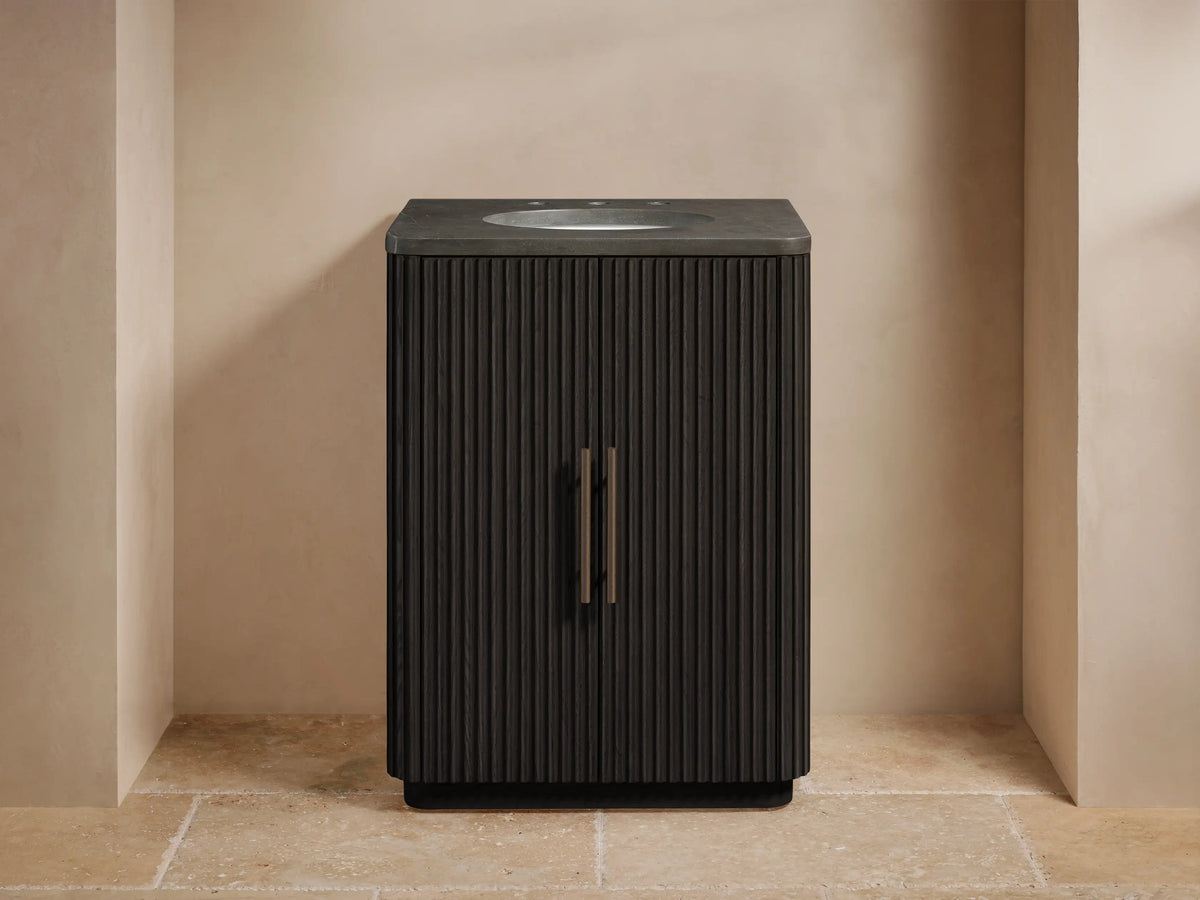 Finnley Powder Vanity: Dark brown fluted cabinet with bronze handles, gray stone top, white oval sink, widespread bronze faucet.