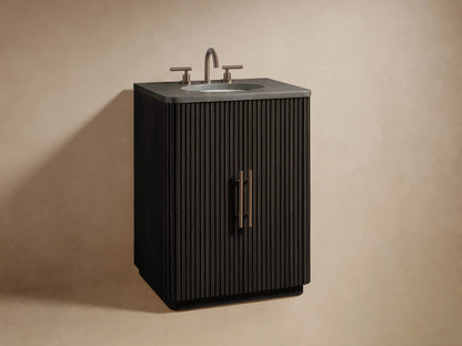 Dark brown Finnley Powder Vanity door with vertical fluting, ajar with brass handle, revealing two bottles and stacked towels.