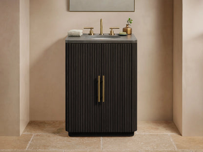Finnley Powder Vanity in dark wood with ribbed texture, features brass hardware, stone top, and mounted sink on beige tiled floor.