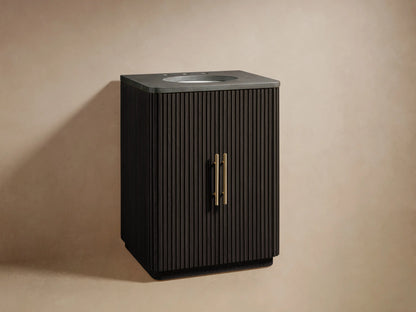 Black oak vanity with vertical fluted design, featuring a dark stone top with an oval sink cutout. Two doors with antique brass handles.