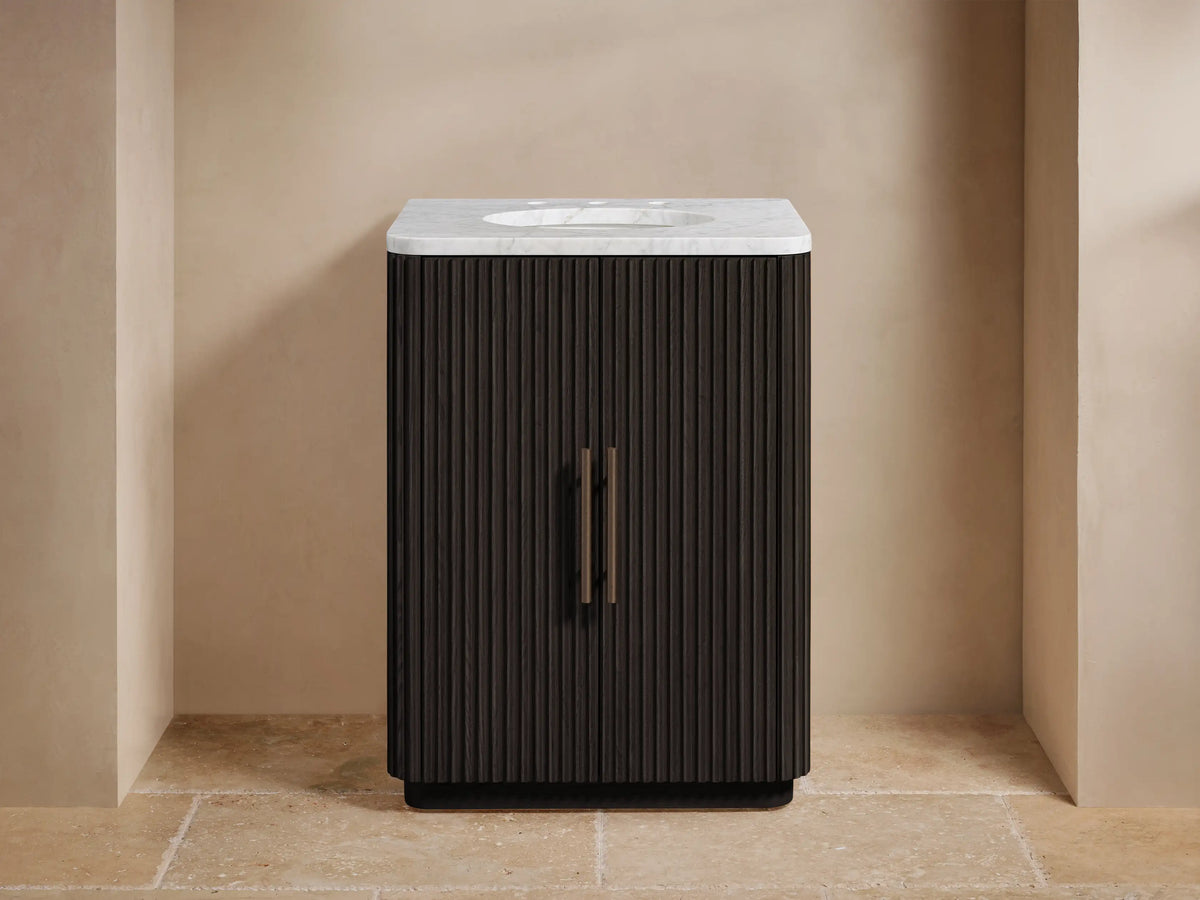 Dark fluted Finnley Powder Vanity with white marble top, dark bronze faucet and handles, in a light-colored bathroom.