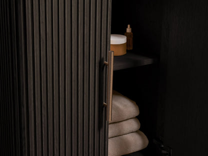 Angled close-up of Finnley Powder Vanity. White marble top with grey veins, oval sink, 3 faucet holes. Dark textured base.