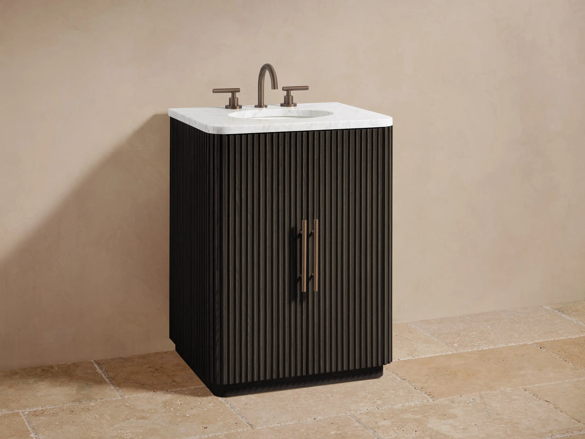 Finnley Powder Vanity: Dark fluted cabinet door partially open, revealing light beige towels and amber/white bottles on dark interior shelves.