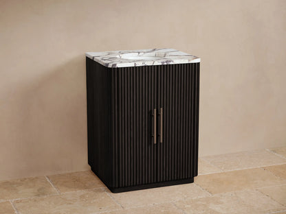 Finnley Powder Vanity: Dark fluted cabinet, white marble top with oval sink, and bronze faucet set, on a light tiled floor.