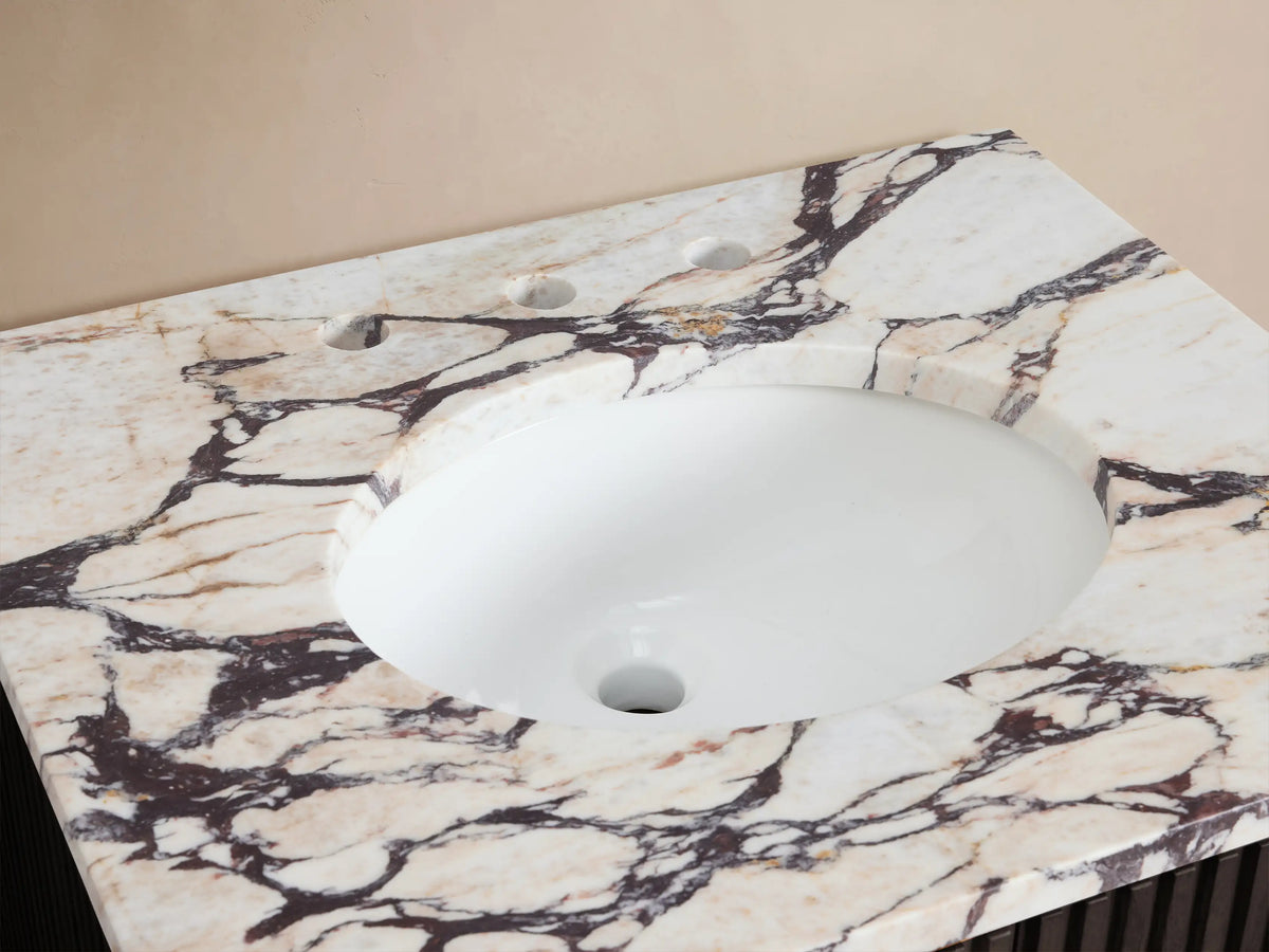 Finnley Powder Vanity, top-down view. Calacatta Viola marble with bold veining, white oval sink, brass faucet, accessories.