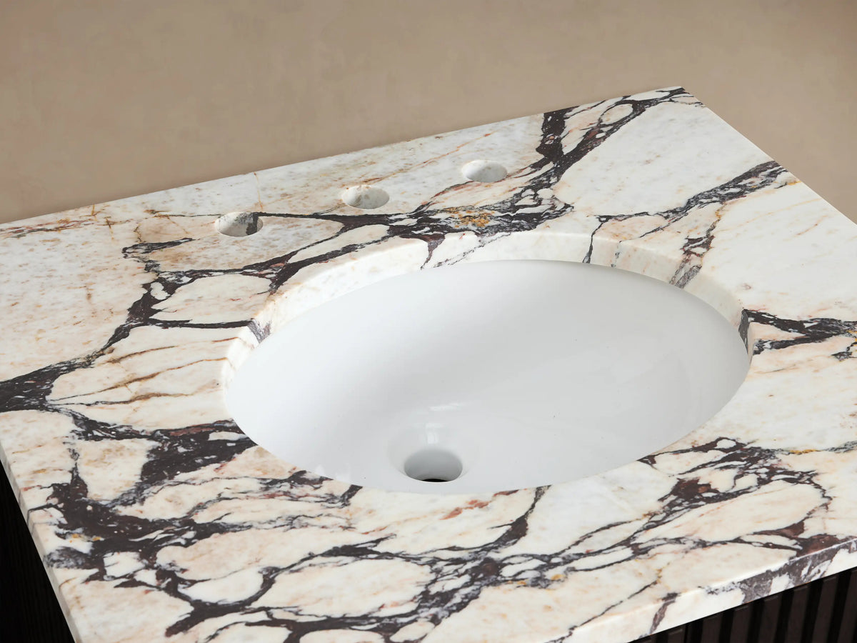 Finnley Powder Vanity: oval white sink, polished nickel faucet on white Carrara marble top with dark veins, towel, soap, flowers.