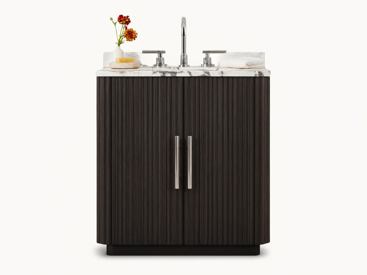 Finnley Powder Vanity with dark brown fluted doors, white veined marble top, chrome faucet & accessories in a neutral bathroom.