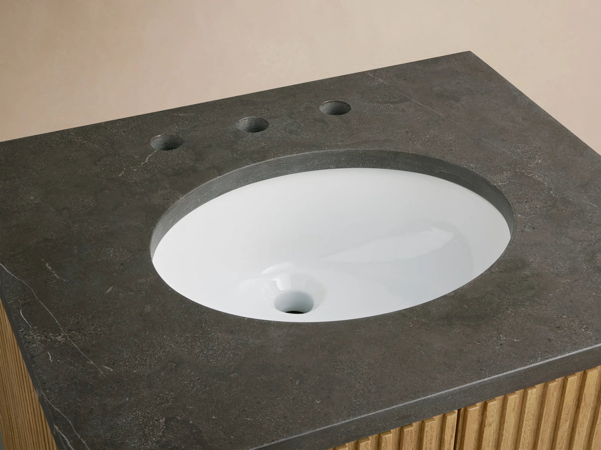 Finnley Powder Vanity: Dark bluestone top with white oval undermount sink, bronze widespread faucet, and slatted oak wood base.