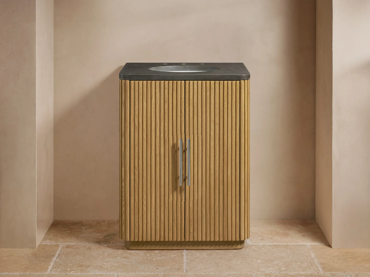 Vanity with vertical oak slat doors, stone top with mounted oval sink, polished nickel handles, and faucet in a neutral-tone bathroom.
