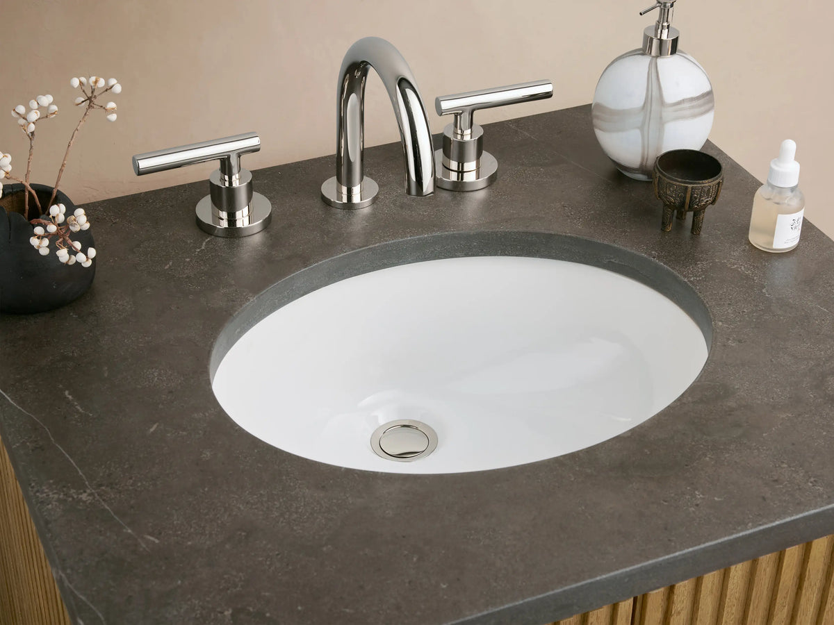 Finnley Powder Vanity with vertical oak wood panels, dark stone top, oval sink, and polished nickel hardware, set against a neutral background.