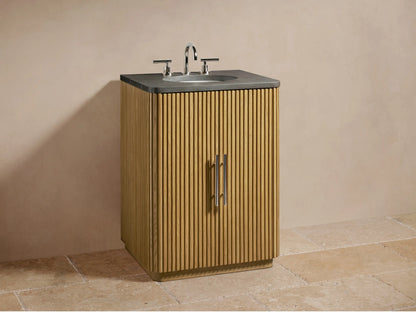 Open door of the Finnley Powder Vanity showing oak wood with vertical grooves, shelves with folded towels, and a small bottle.