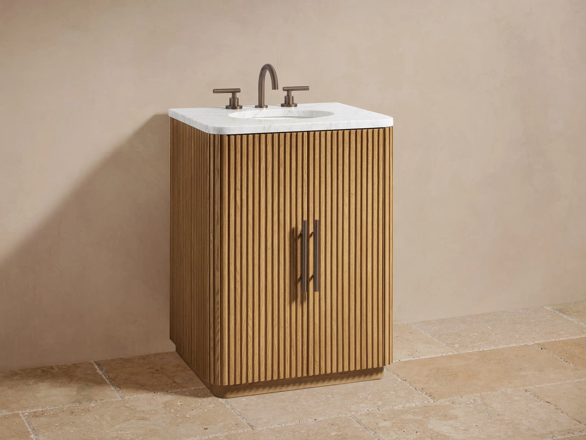 Finnley Powder Vanity: Open oak cabinet door with fluted texture, revealing shelf with white jar, bottle, and stacked grey towels.