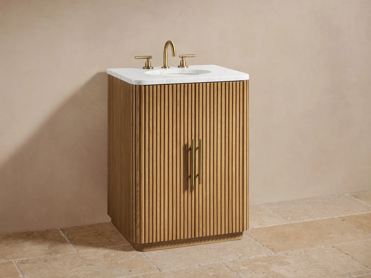 Finnley Powder Vanity oak wood cabinet partially open, showing shelves with folded towels and a bottle, featuring vertical grooves and brass handle.