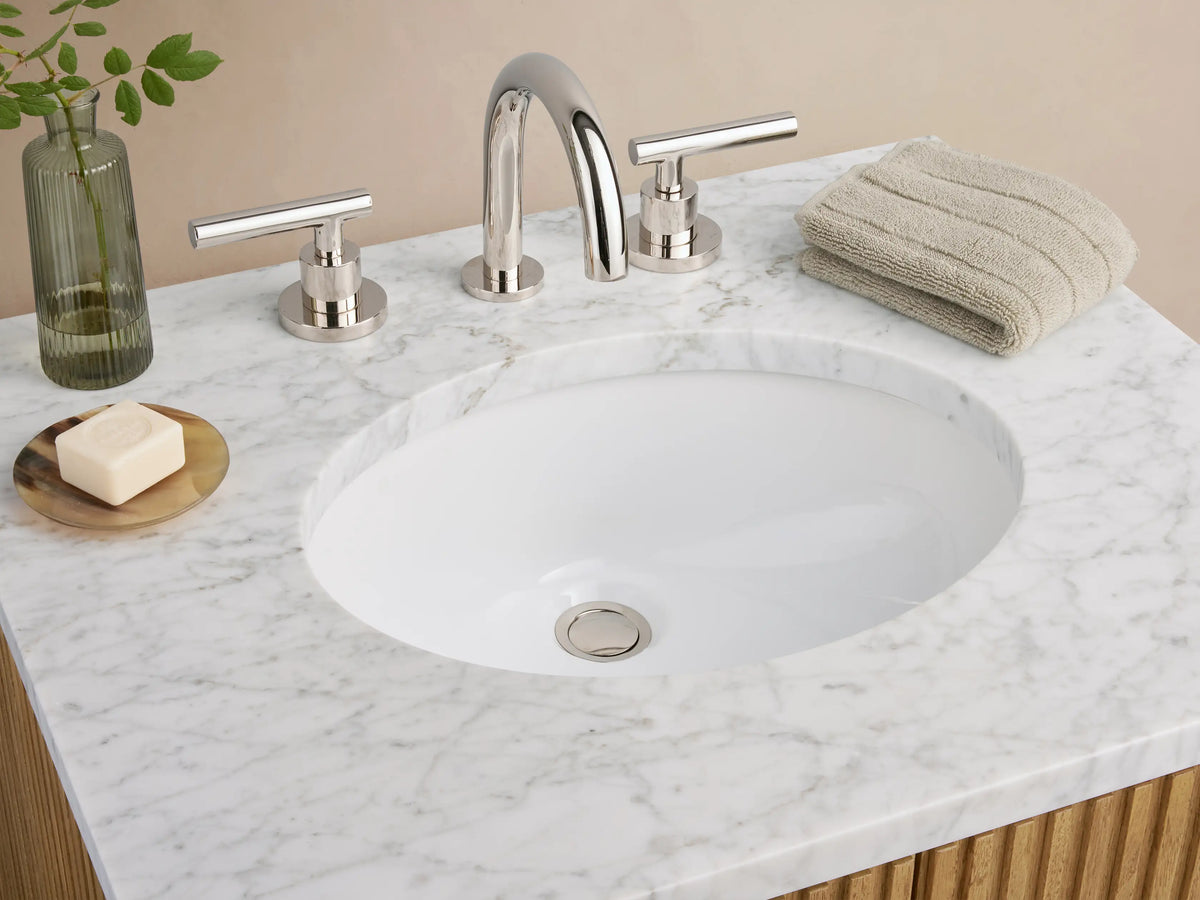 Finnley Powder Vanity with vertical oak wood slats, stone top, oval ceramic sink, and a single polished nickel handle, set against a neutral wall.