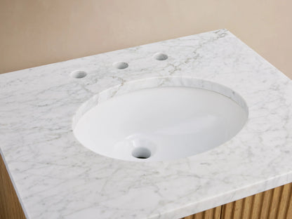 The Finnley Powder Vanity features a Carrara marble top with an oval ceramic sink, chrome faucet, folded towel, and a soap dish.